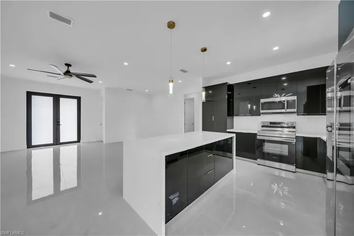 Kitchen with dark cabinets, modern cabinets, stainless steel appliances, decorative light fixtures, and a kitchen island