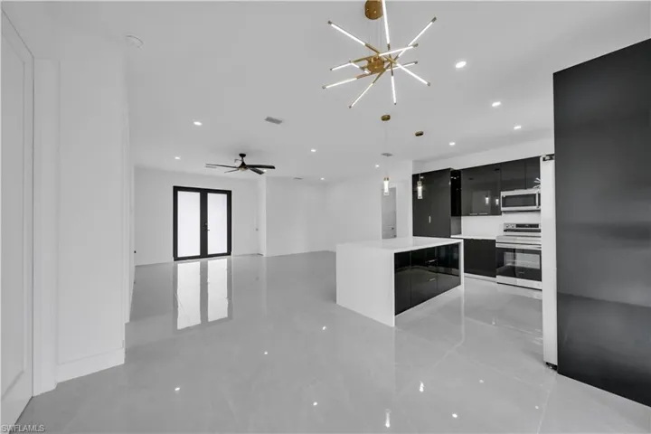 Kitchen featuring dark cabinets, stainless steel appliances, open floor plan, modern cabinets, and pendant lighting