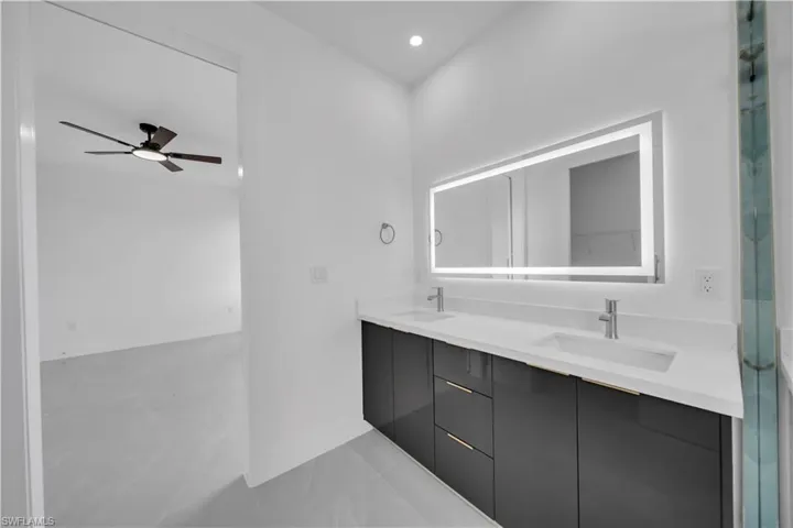 Bathroom with double vanity, an enclosed shower, recessed lighting, and a ceiling fan