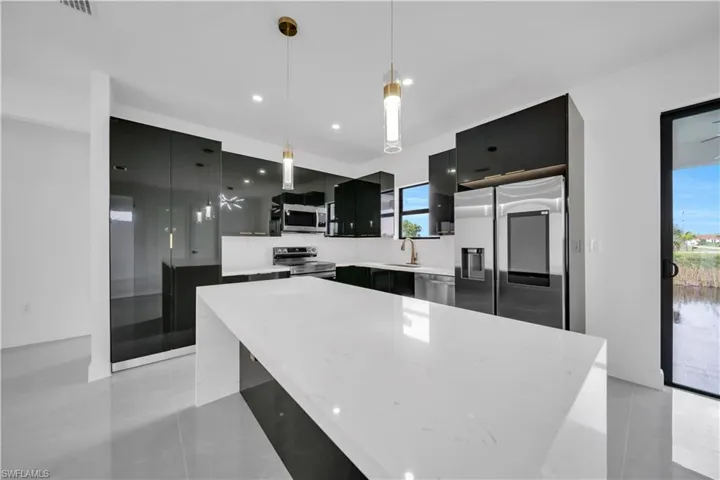 Kitchen featuring dark cabinets, stainless steel appliances, decorative light fixtures, modern cabinets, and a center island