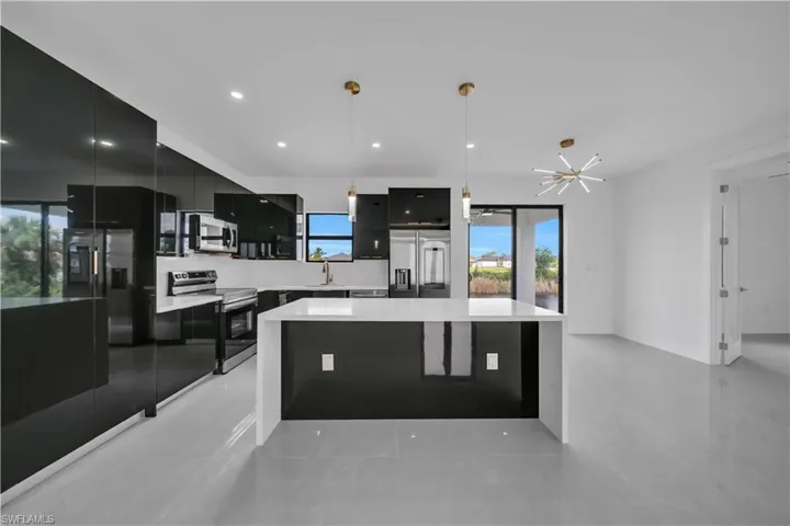 Kitchen featuring dark cabinetry, a center island, stainless steel appliances, hanging light fixtures, and modern cabinets
