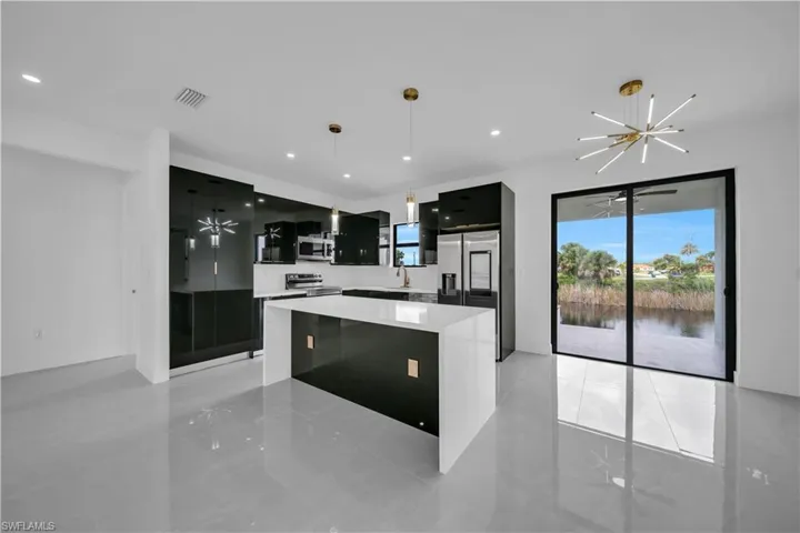 Kitchen with dark cabinets, modern cabinets, a kitchen island, stainless steel appliances, and hanging lights