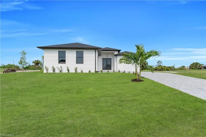View of front of property with a front yard, driveway, and an attached garage