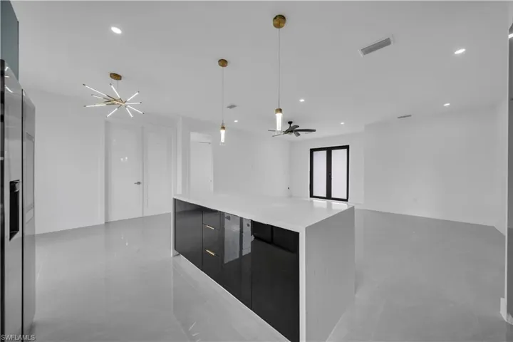 Kitchen with modern cabinets, dark cabinetry, decorative light fixtures, stainless steel fridge with ice dispenser, and a center island