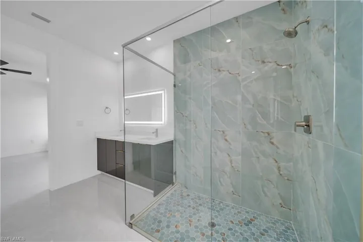 Full bathroom featuring vanity, a marble finish shower, and recessed lighting