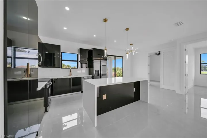 Kitchen with modern cabinets, a kitchen island, stainless steel appliances, light stone countertops, and ceiling fan