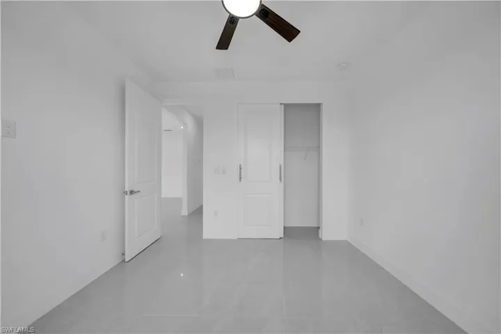Unfurnished bedroom featuring a closet, a ceiling fan, and light tile patterned floors