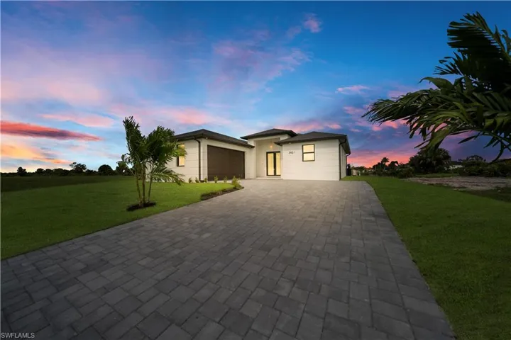 View of front of house with a front lawn, decorative driveway, a garage, and stucco siding