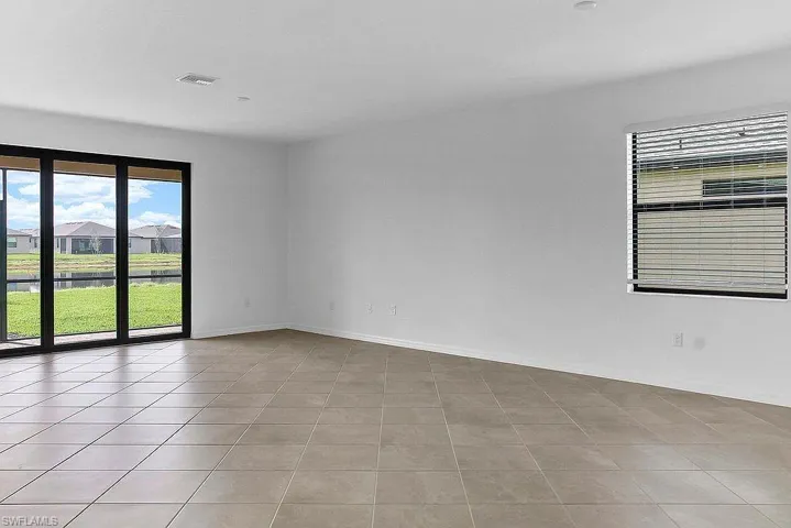 Spacious room with large format floor tiles, white walls, and a recessed ceiling light