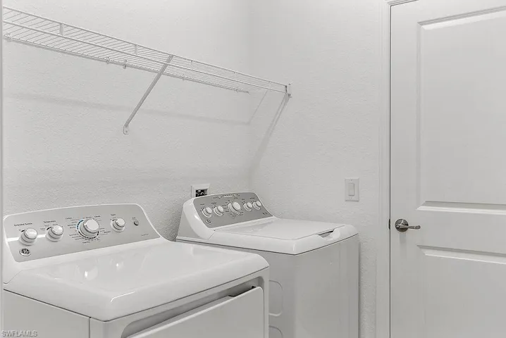 Dedicated utility area featuring white walls and a wire shelving unit