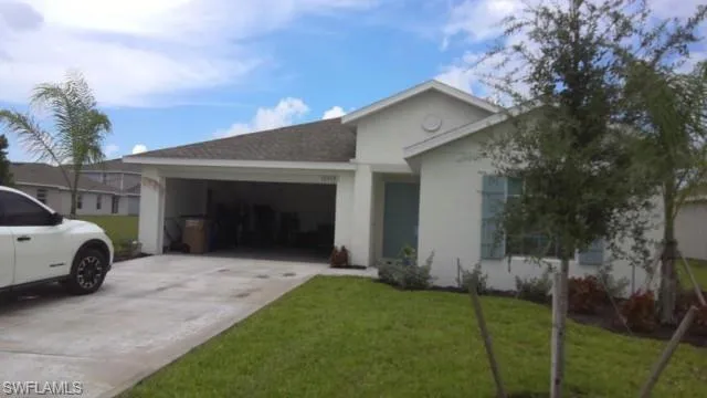 White stucco exterior featuring a brown shingle roof, light blue front door, light blue decorative shutters, and a two-car garage