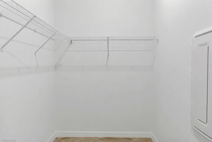 White wire shelving system in a walk-in closet with neutral-toned floor tile and white baseboards