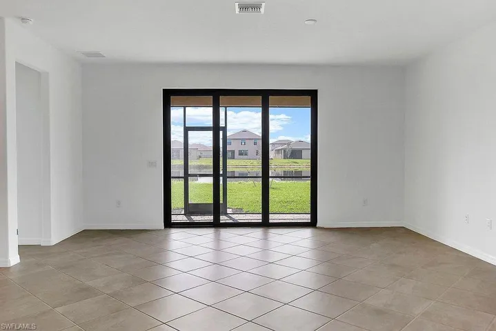 Tiled flooring throughout this open space, featuring a large black-framed sliding glass door with screens