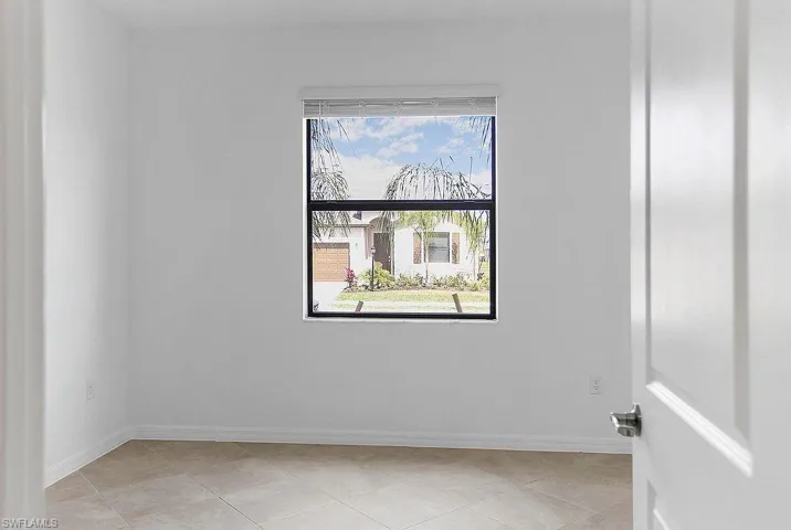 Room featuring neutral wall tones, square tile flooring, white baseboards, and a single window with white blinds
