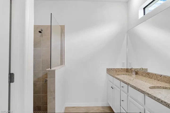 Bathroom featuring a dual vanity with light-toned countertop, integrated sinks, and polished chrome fixtures