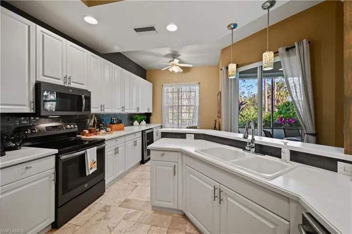 Kitchen with decorative backsplash, ceiling fan, appliances with stainless steel finishes, and white cabinetry