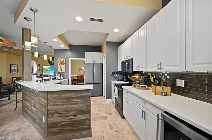 Kitchen with decorative backsplash, stainless steel appliances and white cabinetry