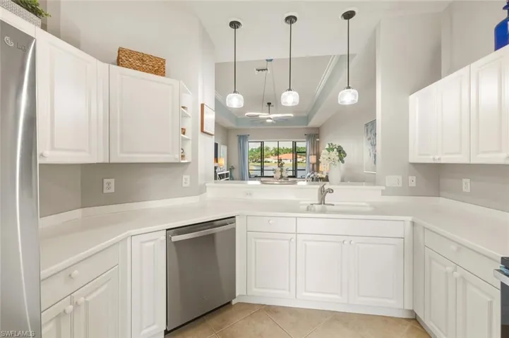 Kitchen with a raised ceiling, white cabinetry, and ornamental molding