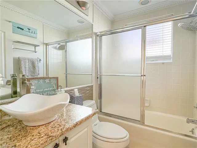 Full bathroom featuring crown molding, toilet, combined bath / shower with glass door, and oversized vanity