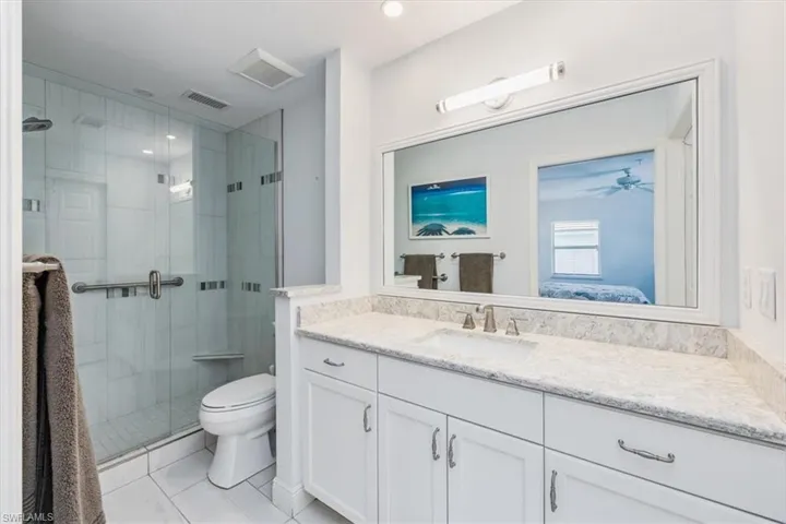 Bathroom with a shower with door, vanity, and toilet