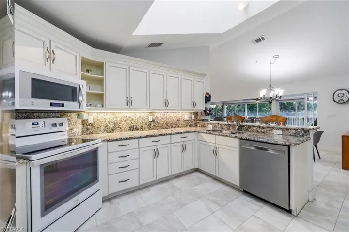 Kitchen featuring white cabinetry, sink, stainless steel dishwasher, and white electric range oven