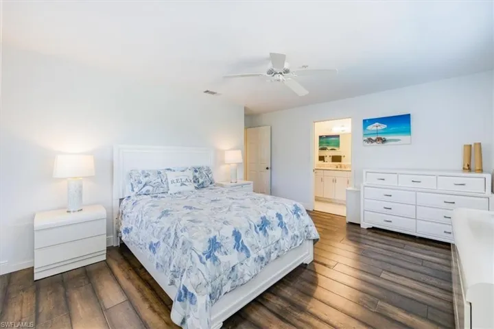 Bedroom featuring ceiling fan, connected bathroom, and dark hardwood / wood-style flooring