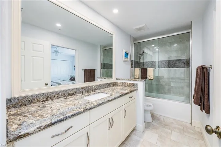Full bathroom featuring enclosed tub / shower combo, vanity, ceiling fan, and toilet