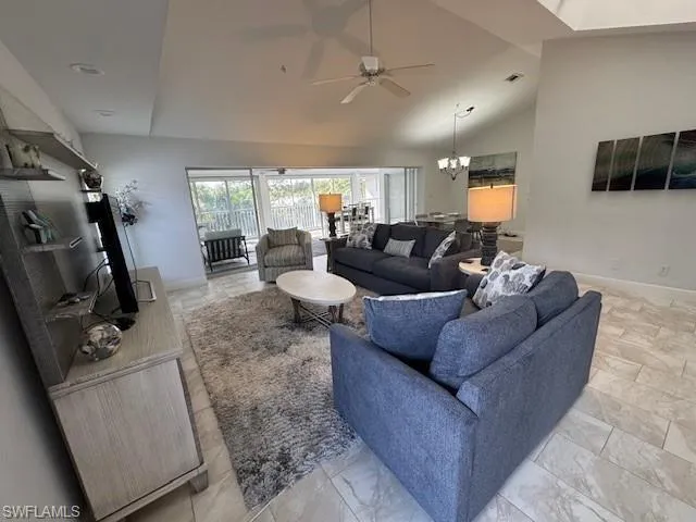 Living area featuring a chandelier, a ceiling fan, and high vaulted ceiling