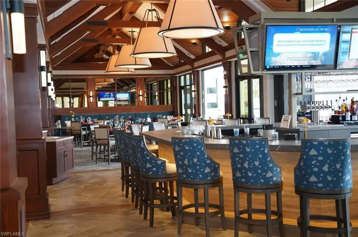 Community bar area featuring lofted ceiling, dark countertops, and decorative light fixtures