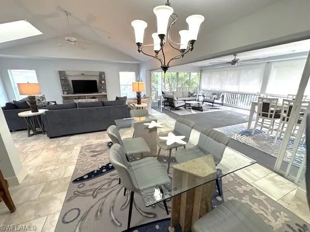 Dining area with a ceiling fan, a chandelier, vaulted ceiling, and a skylight