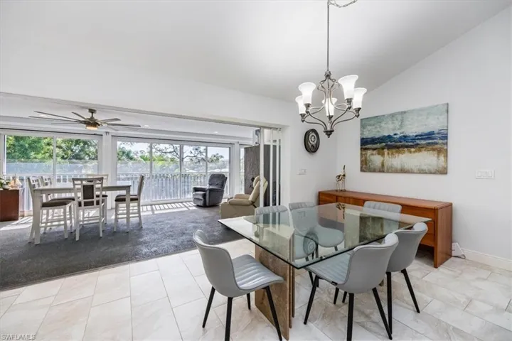 Dining room featuring ceiling fan with notable chandelier and vaulted ceiling