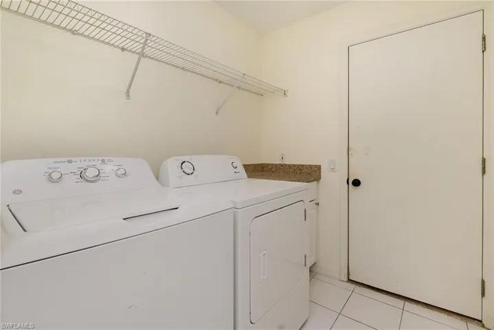 Washroom featuring washing machine and dryer, light tile patterned floors, and cabinet space