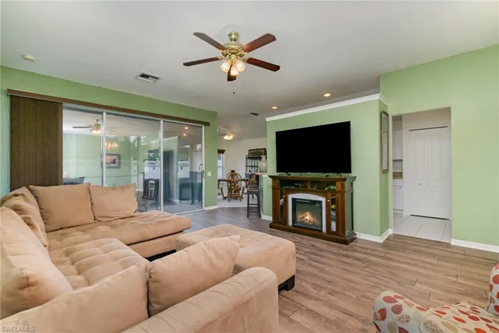 Living room featuring a ceiling fan, wood finished floors, a glass covered fireplace, and recessed lighting