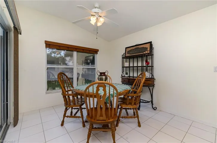 Dining space with lofted ceiling, ceiling fan, and light tile patterned floors
