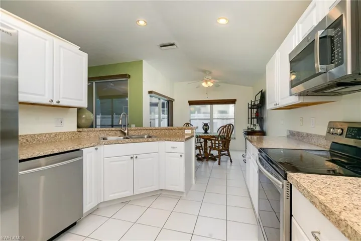 Kitchen with appliances with stainless steel finishes, a ceiling fan, lofted ceiling, light countertops, and a peninsula