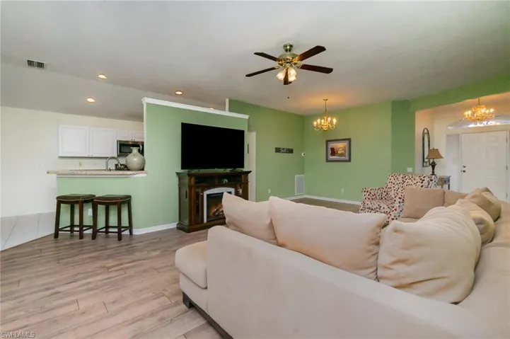 Living area featuring a chandelier, light wood-style floors, recessed lighting, a lit fireplace, and a ceiling fan