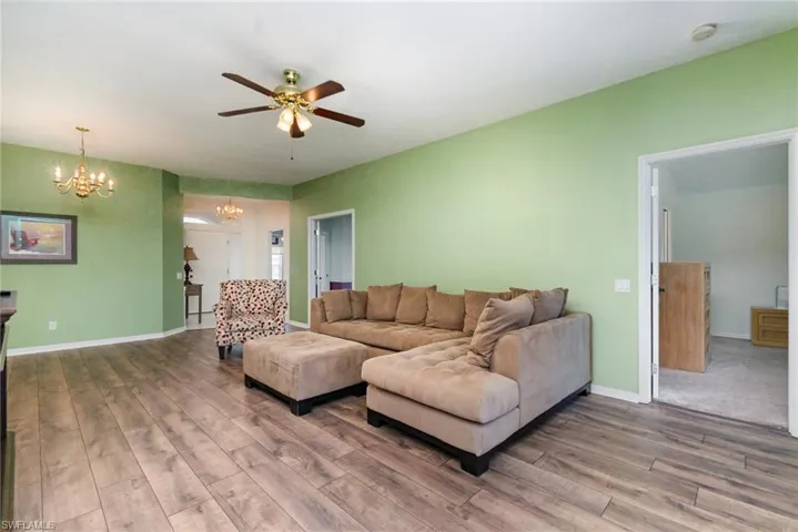 Living room with a chandelier, wood finished floors, and ceiling fan