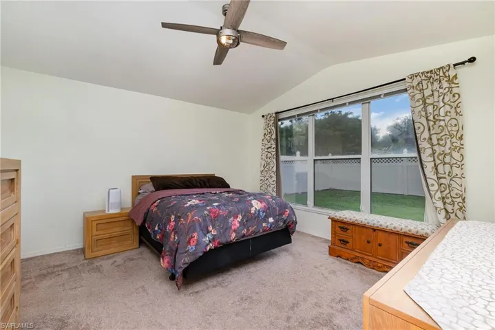 Bedroom with vaulted ceiling, light carpet, and ceiling fan