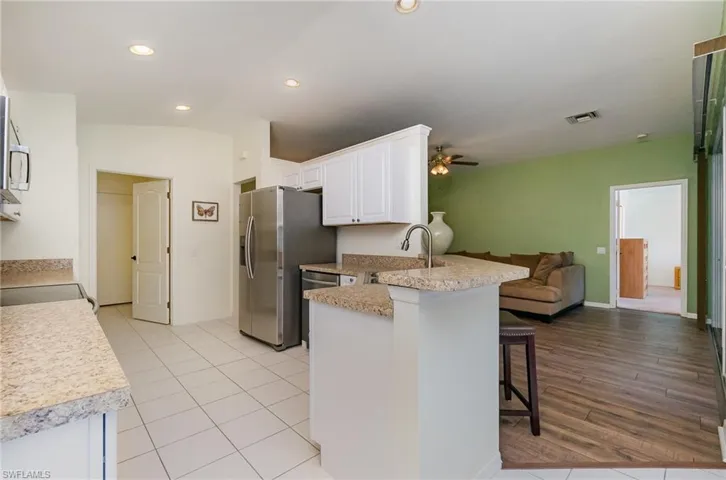 Kitchen featuring a peninsula, open floor plan, a kitchen breakfast bar, ceiling fan, and white cabinetry