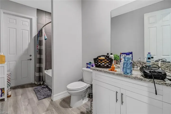 Full bathroom with hardwood / wood-style floors, vanity, toilet, and shower / tub combo with curtain
