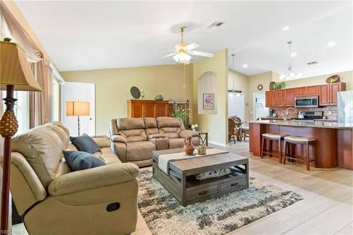 Living room with lofted ceiling, ceiling fan, and light wood finished floors