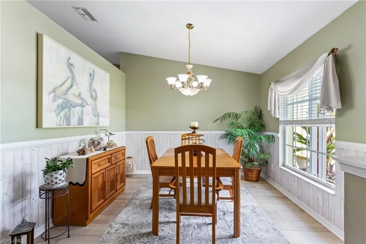 Dining area featuring a wainscoted wall, light wood-type flooring, and a chandelier