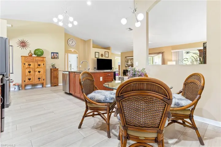 Dining area with vaulted ceiling, arched walkways, light wood-style flooring, baseboards, and a chandelier