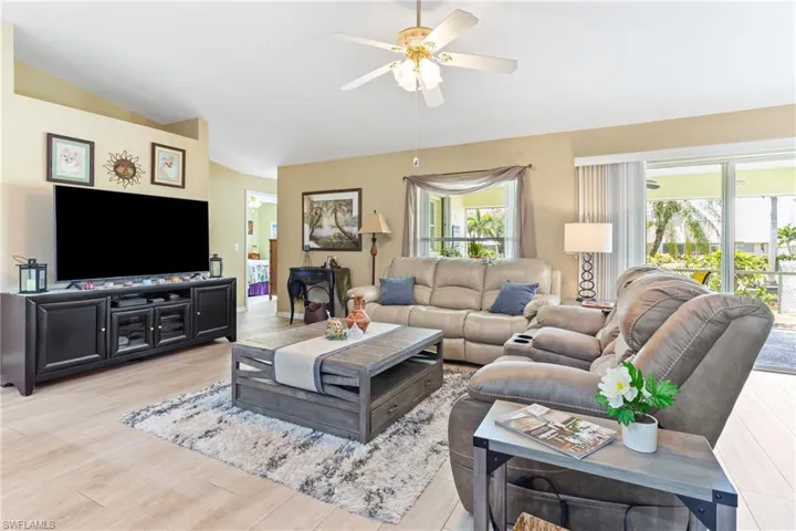 Living room featuring vaulted ceiling, a ceiling fan, and light wood-style floors