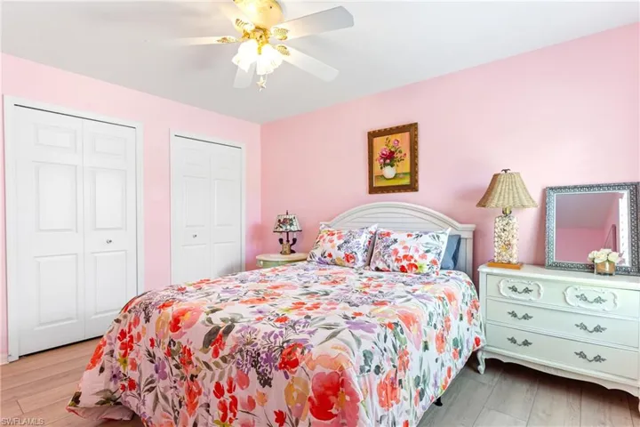 Bedroom with two closets, wood finished floors, and a ceiling fan