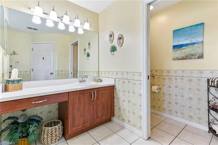 Bathroom with a wainscoted wall, vanity, and tile patterned floors