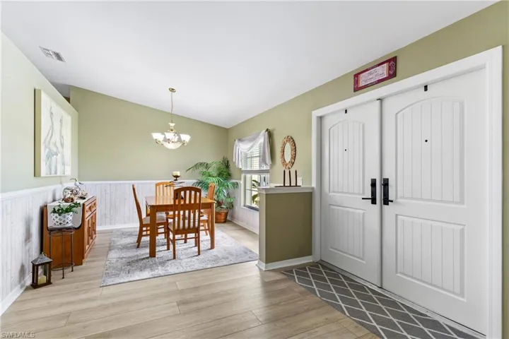 Foyer entrance featuring a chandelier, wood finished floors, a wainscoted wall, and baseboards