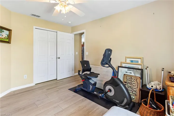 Workout room with wood finished floors, ceiling fan, and baseboards