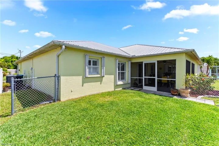 Back of property with stucco siding, a sunroom, metal roof, and a ceiling fan