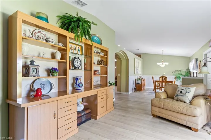 Home office with arched walkways, light wood finished floors, and a chandelier